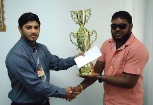 Sandeep Ramdass, Managing Director of Ishmail Poultry Establishment presents trophy and cash incentive for the man of the match of the final to Mahendra Ramdihall, representative of the BCB. 