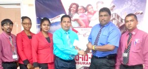  BCB Senior Executive Anil Beharry (right) collecting sponsorship cheque from Tajpaul Adjodhea Berbice Area Manager of Hand in Hand Group of Insurance Company in the presence of other staff members. 