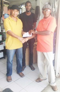 Mark Lewis of Lewis and Sons General Store  at Rose Hall Town presents the cheque to Coordinator Randolph Roberts (right).  Also sharing the moment is Neil Lewis. 