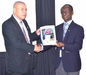 PAHO Representative, Dr William Adu-Krow (right) hands over a copy of the Cancer Surveillance Report to Minister of Public Health, Dr George Norton. 