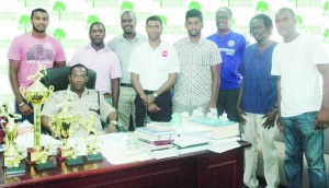 Commander Clifton Hicken (seated) is surrounded by National Cricketers,  Paul Wintz, Robin Bacchus and Steven Jacobs, along with some members  of the media, Errol Nelson Banks DIH Water Brand Manager (on his left). 