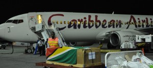 Director of Sport Christopher Jones puts the Guyana flag on Gordon Sandiford’s remains just after it arrived in Guyana Tuesday. 