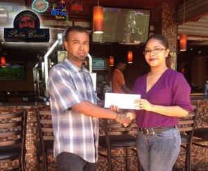 Manager of Palm Court Sasha Lewis presents the cheque to Rovin De Souza of the Guyana Cup Organising Committee. 