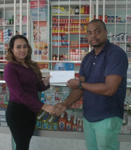 Medicine Chest Pharmacy Manager, Amanda Doodnauth (left) hands over their contribution to Edison Jefford yesterday at the Middle Street location of the Pharmacy.