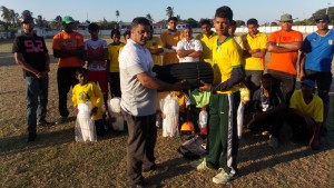  Ajaz Asgarally presents a batting pad to the club’s U15 Captain Aftab Bashir in the presence of members of the club. 