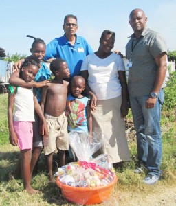 Food Drive recipient, Amanda Welch, and her children in the company of FFTP’s Field Officer, Compton Giddings,  (at centre), and Senior Manager, Jimeel Davis, (at extreme right).