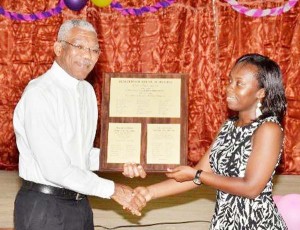 Vice President of the Guyana Nursing Association, Teona Greene-Eririogu receiving a plaque from President David Granger.