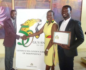 Guyana’s 50th Independence Anniversary logo, creator Compton Babb and Christopher Taylor in the company of Minister Nicolette Henry. The Logo was launched on Friday at the National Cultural Center.