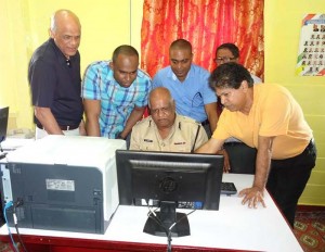 Police Commissioner (Ag) Balram Persaud tries out one of the computer systems with direction from Naresh Singh, New York based IT consultant as Jay Sobhraj a Director of the Zara Group and Crime Chief Wendell Blanhum look on. 