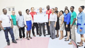 Toshao of Santa Aratak Mission Aubrey Samuels poses with the cheque in the presence of GTT officials and members of the Organising Committee of the event.