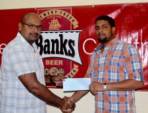 Gavin Jodhan (left) Branch Controller of Banks DIH presents the cheque to Coordinator Nazrudeen Jumbo Jet Mohammed. 