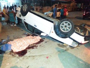 A sheet covers Rakesh’s body next to his overturn car