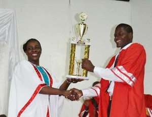 Minister Nicolette Henry presents a trophy to Best Graduating Student, Kedon Stewart. 