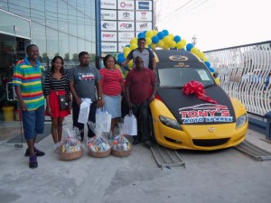 Ayube Khan stands at the door of his Mazda RX-8 sports car flanked by some of the other winners of consolation prizes.