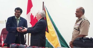 Canadian High Commissioner to Guyana Mr. Pierre Giroux hands over a piece of the equipment to Minister of Public Security Mr. Khemraj Ramjattan, while Commissioner of Police Mr. Seelall Persaud, DSM looks on appreciatively.