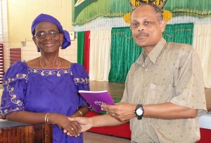 Ms. Esther Utoh hands over a copy of Dr. Hunte’s book to Mr. Paul Cameron which is expected to aid CPCE’S pastoral care initiative.