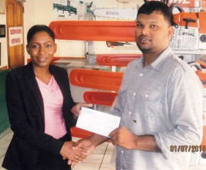 Ms. Novella Perriera, Cashier at Farfan and Mendes Ltd. presents the cheque to Mark Papannah of RHTY&SC. 