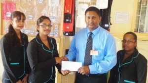 Ms. Padmini Ramsammy of N.P.G Packaging & Plastic Inc hands over the sponsorship cheque to Mr. Vicky Bharosay, Treasurer of the UCCA. Also in photo are staff members of N.P.G Packing & Plastic Inc.