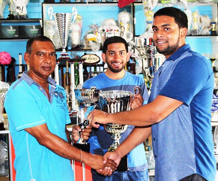 Proprietor of Trophy Stall Ramesh Sunich presents a collection of trophies to Nazrudeen Jumbo Jet Mohammed Jr at the Trophy Stall.