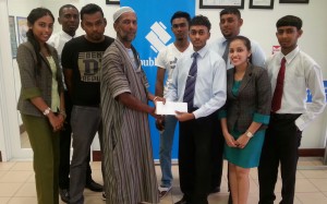 Treasurer of the Blairmont CC Shizad Ali (left) accepts the sponsorship cheque from a representative of Republic Bank in the presence of other staff and members of the club. 