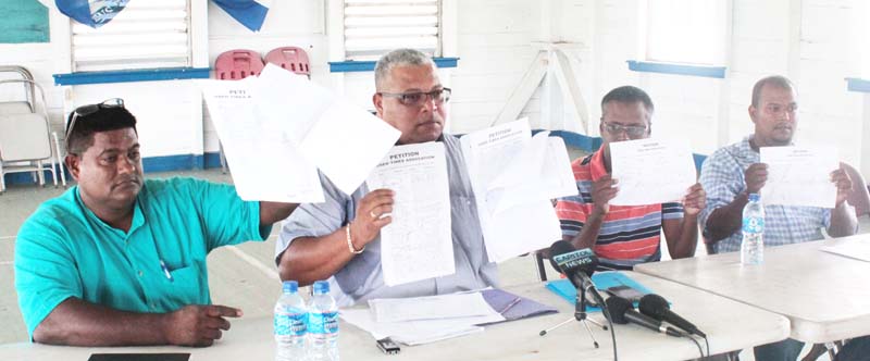 President of the Guyana Used Tyres Association (GUTA), Allan Newark (second from left), along with other committee members, displaying the signatures of petitioners. 