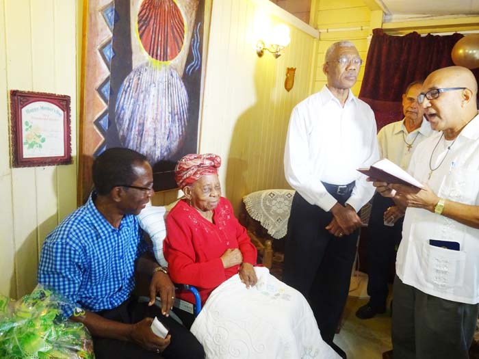 President Granger joins in prayer with centenarian Mrs. Olive Blackmore.