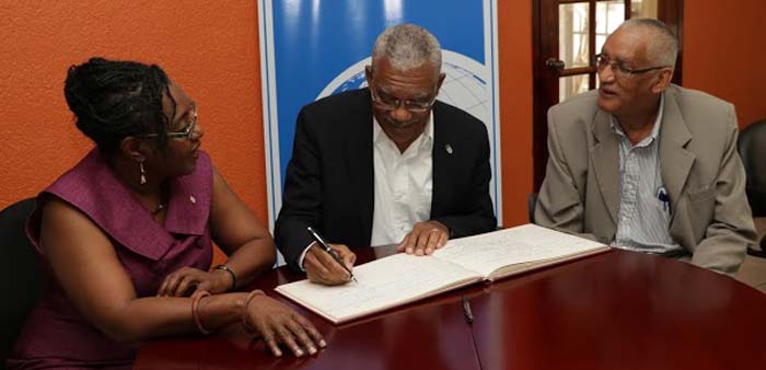 President Granger signing the Guest book at the Institute of International Relations. He is flanked by Guyanese Dr. Mark Kirton and Trinidadian Scholar, Professor Rhoda Reddock.