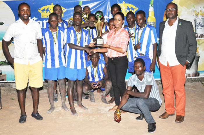 Royal Youths Captain Marvin Sullivan proudly collects the trophy from Ms Lise Lewis of Top Brandz Distributors, local agents of Corona Beer in the presence of teammates. 