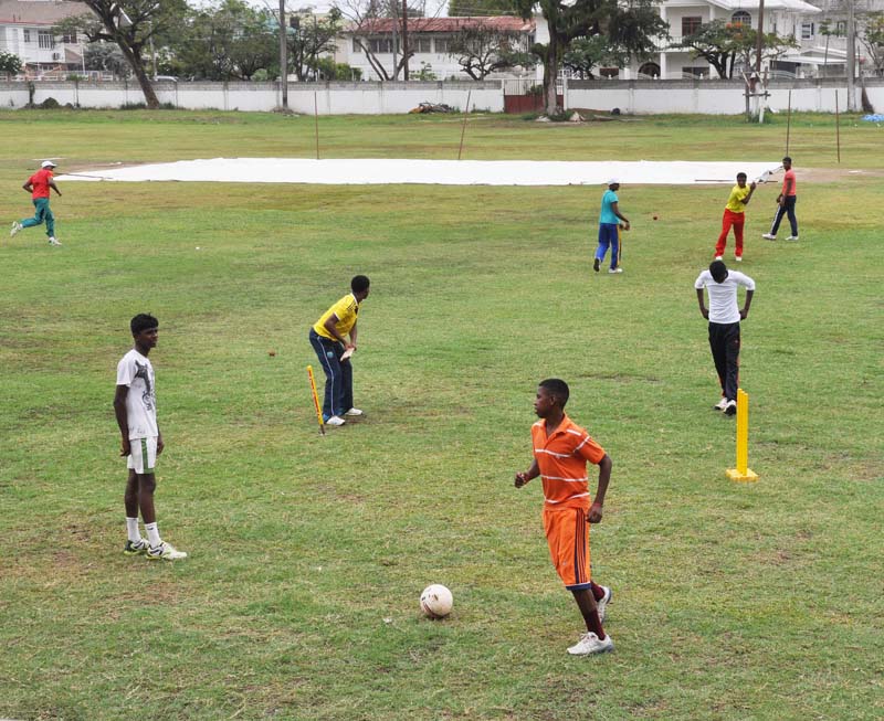 The inadequately covered pitch and the players playing Football and cricket at DCC yesterday morning. 