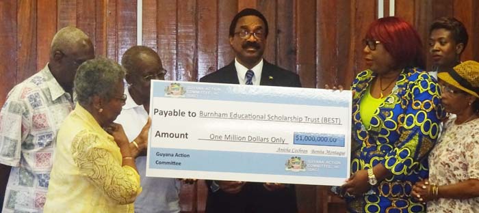 Members from GAC (right) presenting the million dollar cheque to members of BEST (left) in the presence of Attorney General Basil Williams (Centre).