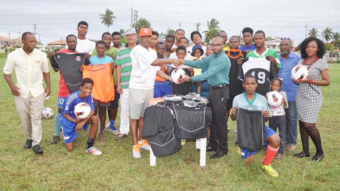 Mark Fanfair (left) hands over one of the balls to CFC President Romel Richmond as club members display some of the other donated items.
