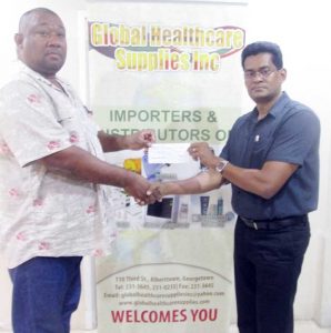 RHTYSC, MS Secretary/CEO Hilbert Foster (left) receives cheque for trophies from Global CEO Deonarine Etwaroo.