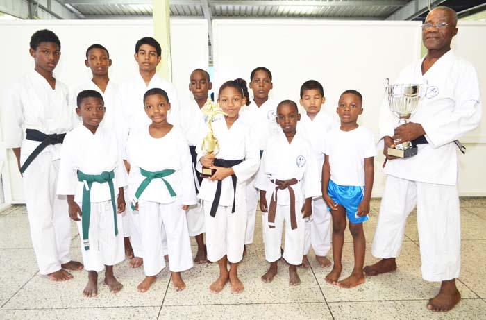 Sensei Winston Dunbar and Sadella Britton holding trophies, with some of the participants after the event.