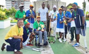 Some of the Differently Abled Athletics Club members along with Director of Sport Chris Jones (centre) Former Prime Minister Sam Hinds (stooping left)  with William France next to the PM following the presentation.