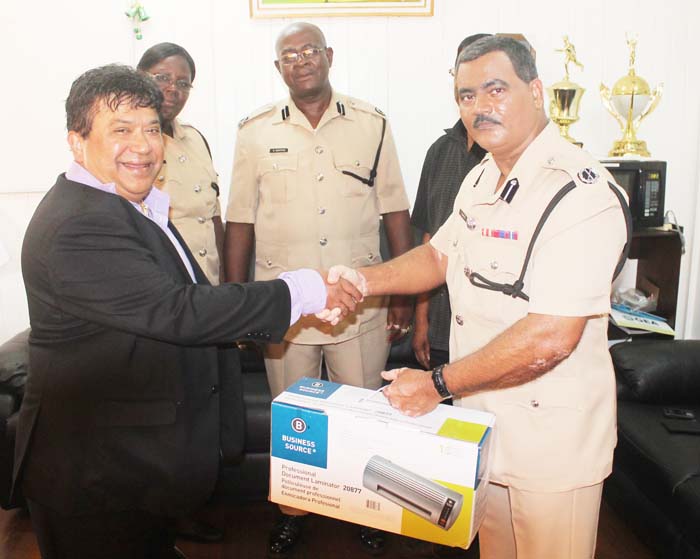 Dr. Roberto Jacgobin hands over the document laminator to Assistant Commissioner David Ramnarine, while Senior Superintendent Maxine Graham, Assistant Commissioner “Operations” Christopher Griffith and Force Chaplain Pastor Patrick Doolichand (partly hidden) look on.