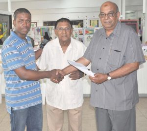 Atwell collects a cheque from General Secretary of CIOG Khakan Ramjohn while Treasurer Khalilhalil Ahmed shares the moment. 