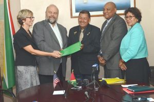 US Ambassador to Guyana Perry Holloway hands over the MoU to Minister of Indigenous Peoples’ Affairs Sydney Allicock (centre). Also in photo are Minister of Natural Resources Raphael Trotman (second from right), Minister within the Ministry of Indigenous Peoples’ Affairs Valerie Garrido-Lowe (right), and Country Director, Peace Corps-Guyana Linda Arbogast (left) (GINA photo).