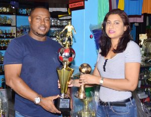 Petra Organization Co-Director Troy Mendonca collects the trophies from Trophy Stall representative Devi Sunich yesterday.