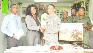 GDF Welfare Officer Deon Heyligar receives the donation from U.S. Army Captain Christopher Hill. Looking on are Asst. Force Chaplain George Jeffers, members of the Welfare Department and other soldiers.