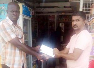 Organiser Samuel Kingston (left) accepts the cheque from Davindra Gangaram of Dave’s Groceries and Variety Store. 