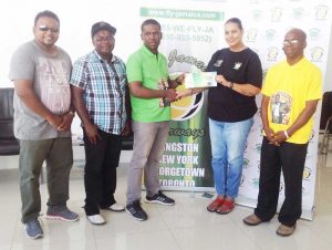 A Fly Jamaica representative presents the tickets to NYC to Atwell in the presence of three members of his committee. 