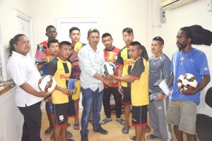 Excel Minerals Inc representative Devon Winter (centre) presents one of the balls to Paramakatoi Secondary Captain Reon Peters on Saturday.