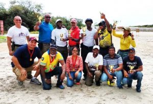 The top four teams at Sunday’s GuyanaNRA / Modern Optical Service Combat Pistol Team Shoot display their silverware. Dr. Johan DaSilva is stooping left while Smallbore Captain Dale Hing is standing left. 