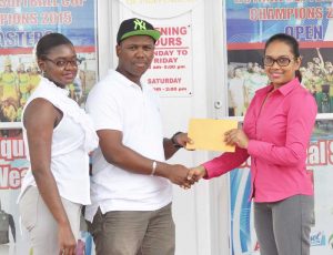 - Clive Atwell (left) accepts the cheque from Telesha Ousman of Regal Stationery and Computer Centre in the presence of his wife Altavi Atwell. 