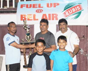 Ramesh Sunich (left) of Trophy Stall handing over the winning trophy to Anil Persaud of East Coast Cricket Committee in the presence of two Under-15 players and GFSCA representative Anil Beharry.