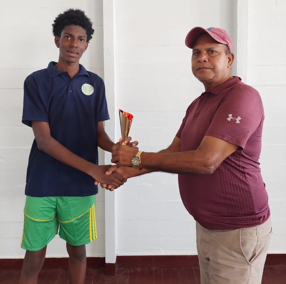 Jonathan Mentore receives the man of the match trophy from Match Referee Moses Ramnarine.