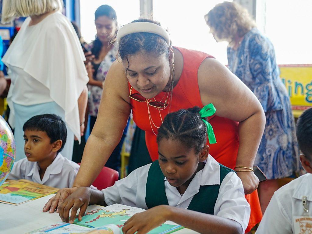 Minister of Education, Priya Manickchand reading with a student of the Mon Repos Primary School at Saturday’s opening of the school’s library.