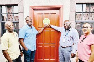 Proprietor Kurt French and GNBS Director (ag) Al Fraser attach the certification sticker on one of the rooms