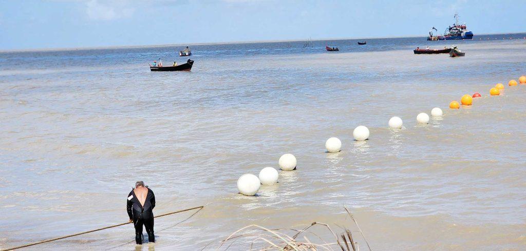 Technicians rolling out the subsea cable at the Kingston, Georgetown Beach earlier this year