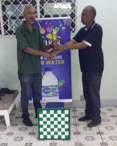 Dr. Ivor English (right) presents the winning trophy to Navin Meighbarran.